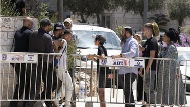 Israeli settlers watch the police arrest a left-wing activist in a demonstration near the home of the far-right Minister of National Security, Itamar Ben Gvir (AP)