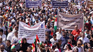 People lift banners during a rally in Dohuk city in the autonomous Kurdish region of northern Iraq on September 5, 2023, to protest unpaid salaries for civil servants for which they hold the Baghdad federal government responsible, and in support of Kurds in Kirkuk. (AFP)