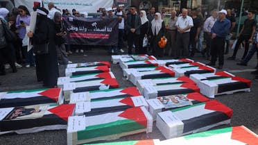Protesters stand by mock coffins covered with the Palestinian flag as they demand the return of the bodies of their slain relatives held by Israeli forces, during a rally in Nablus city in the occupied West Bank on August 27, 2023. (AFP)