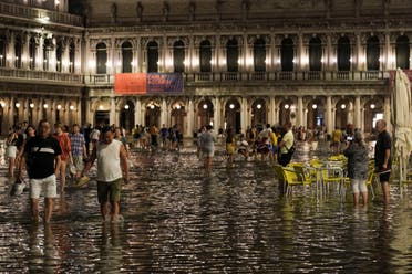 Tourists walk through flooded St Mark's Square after unusually high water levels in Venice, Italy, August 1, 2023. (Reuters)