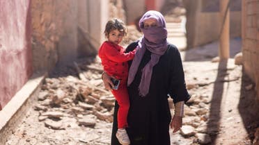 سيدة مغربية تحمل ابنتها قرب منزلها المدمر - أسوشييتد برس