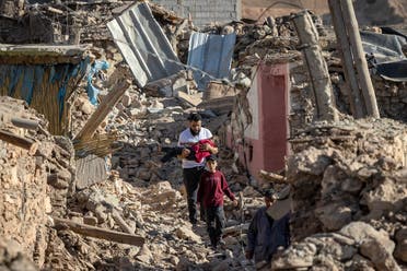 People walk past destroyed houses after an earthquake in the mountain village of Tafeghaghte, southwest of the city of Marrakesh, on September 9, 2023. (AFP)