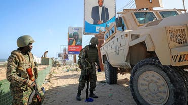 Ugandan peacekeepers with the African Transition Mission in Somalia (ATMIS) stand next to their armored vehicle, with a campaign poster for presidential candidate Ahmed Abdullahi Samow seen above, on a street in Mogadishu, Somalia Tuesday, May 10, 2022. Somalia is set to hold its long-delayed presidential vote on Sunday, ending the convoluted electoral process that raised tensions in the country when the president's term expired last year without a successor in place. (AP Photo/Farah Abdi Warsameh)