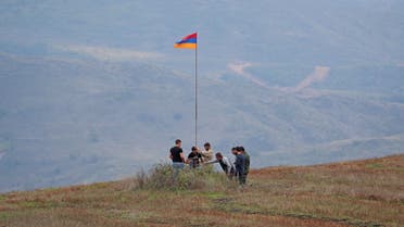 Men install an Armenian flag next to a checkpoint on the road leading to Azerbaijan's Nagorno-Karabakh region, near the village of Kornidzor, Armenia September 22, 2023. REUTERS/Irakli Gedenidze