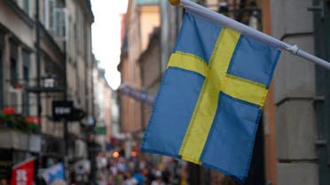 A Swedish flag hangs outside a store on a busy street as visitors walk past in the background in the old town of Stockholm, Sweden, July 14, 2023. (Reuters)