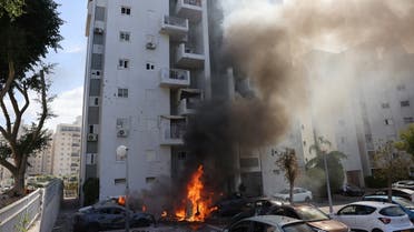 Cars parked outside a residential building catch fire during a rocket attack from the Gaza Strip on the southern Israeli city of Ashkelon, on October 7, 2023. (AFP)