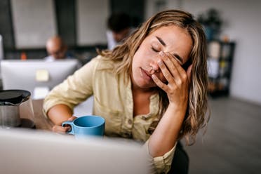 An exhausted woman drinking coffee while working at her computer. (Stockphoto)