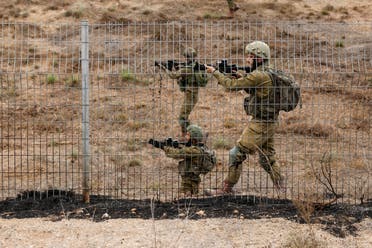 Israeli soldiers scan an area while sirens sound as rockets from Gaza are launched towards Israel,, near Sderot, southern Israel, October 9, 2023. (Reuters)