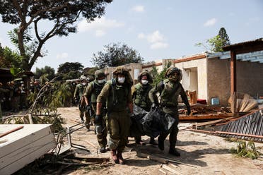 Israeli soldiers carry the body of a victim of an attack by militants from Gaza at Kibbutz Kfar Aza, in southern Israel, October 10, 2023. (Reuters)