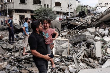  A man carries a crying child as he walks in front of a building destroyed in an Israeli air strike in Gaza City on October 7, 2023. (AFP)