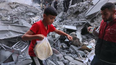A Palestinian youth carries bread amid the rubble of the city center of Khan Yunis in the southern Gaza Strip following Israeli shelling on October 10, 2023. (AFP)