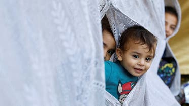 Palestinian children who fled their homes due to Israeli strikes look through a makeshift tent as they shelter at al-Shifa hospital in Gaza City, on October 12, 2023. (Reuters)