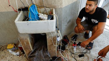 Palestinians charge their mobile phones from a point powered by solar panels provided by Adel Shaheen, an owner of electric appliances shop, as electricity remains cut during the ongoing Israeli-Palestinian conflict, in Khan Younis in the southern Gaza Strip October 14, 2023. REUTERS/Ibraheem Abu Mustafa