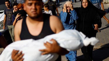 A man carries the body of a Palestinian child killed in Israeli strikes as mourners react, outside a hospital in Khan Younis in the southern Gaza Strip, October 17, 2023. REUTERS/Mohammed Salem