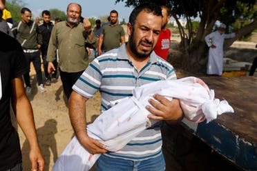 A mourner carries the body of a child, during the funeral of Palestinians from al-Astal family, who were killed in Israeli strikes, in Khan Younis in the southern Gaza Strip, October 22, 2023. (Reuters)