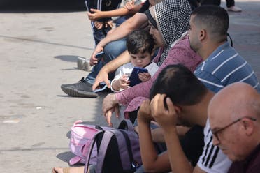 Palestinians with duel citizenship wait outside the Rafah border crossing with Egypt on October 21, 2023, as they wait for permission to cross.