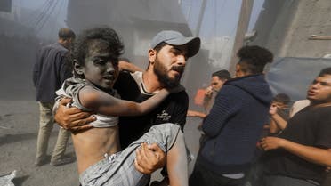 A Palestinian man carries a child  at the site of Israeli strikes on houses, in Khan Younis in the southern Gaza Strip, October 26, 2023. (Reuters)