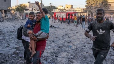 A wounded Palestinian man carries children following a strike in Rafah on the southern Gaza Strip on November 6, 2023, amid the ongoing battles between Israel and the militant group Hamas. (AFP)