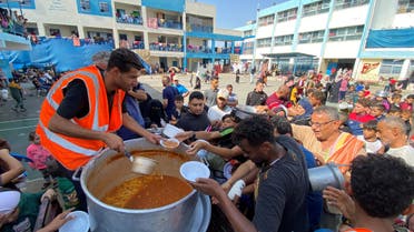 Palestinians, who fled their houses due to Israeli strikes, gather to get their share of charity food offered by volunteers, amid food shortages, at a UN-run school where they take refuge, in Rafah, in the southern Gaza Strip, October 23, 2023. REUTERS/Mahmoud al-Masri