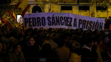 Demonstrators hold a banner reading ‘(Spain’s Prime Minister) Pedro Sanchez in prison’ during a protest against government negotiations for granting an amnesty to people involved with Catalonia’s failed 2017 independence bid, near to the Spanish Socialist Party (PSOE) headquarters in Madrid, on November 8, 2023. (AFP)