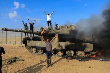 Palestinians celebrate as an Israeli military vehicle burns after it was hit by Palestinian gunmen who infiltrated areas of southern Israel, at the Israeli side of Israel-Gaza border, October 7, 2023. (Reuters)