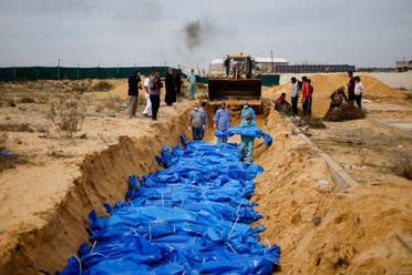 The bodies of Palestinians killed in Israeli strikes and fire are buried in a mass grave, after they were transported from Al Shifa Hospital in Gaza City for burial, in Khan Younis in the southern Gaza Strip, on November 22, 2023. (Reuters)