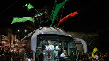 A bus transporting Red Cross staff and Palestinians prisoners released from Israeli jails in exchange for hostages released by Hamas from the Gaza Strip, drives through supporters holding flags in Ramallah in the occupied West Bank early on November 26, 2023. (AFP)