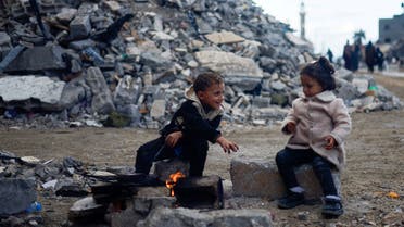 Palestinian children sit by the fire next to the rubble of a house hit in an Israeli strike during the conflict, amid a temporary truce between Hamas and Israel, in Khan Younis in the southern Gaza Strip November 27, 2023. REUTERS/Mohammed Salem