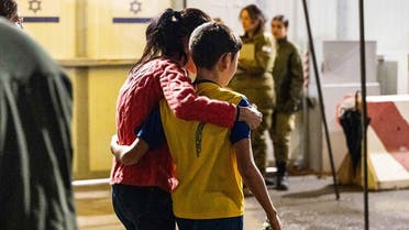 This handout picture released by the Israeli Defence Forces (IDF) shows former Israeli hostage 12-year-old Eitan Yahalomi (R) reunited with his mother following his release by Hamas from the Gaza Strip, at the Kerem Shalom meeting point early on November 28, 2023. (AFP)