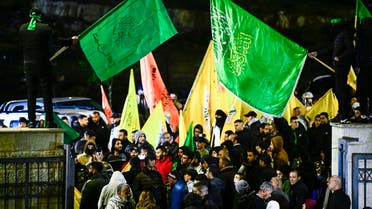 Palestinians wave Hamas flags as they wait for the release of prisoners in exchange for Israeli hostages held by Hamas, in Ramallah in the occupied West Bank on November 27, 2023. (AFP)