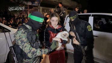 A dog is held as hostages who were abducted by Hamas gunmen during the October 7 attack on Israel, are handed over by Hamas militants to members of the International Committee of the Red Cross, as part of a hostages-prisoners swap deal between Hamas and Israel amid a temporary truce, in an unknown location in the Gaza Strip, in this screengrab taken from video released November 28, 2023. Hamas Military Wing/Handout via REUTERS