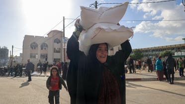 Palestinians receive bags of flour at the United Nations Relief and Works Agency for Palestine Refugees (UNRWA) distribution center in the Rafah refugee camp in the southern Gaza Strip on November 21, 2023. (AFP)