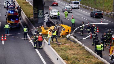 Emergency workers stand next to a helicopter that crashed on a Madrid motorway ring road, hitting a car and injuring people, in Madrid, Spain, on December 1, 2023. (Reuters)