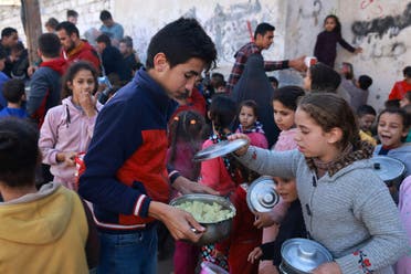 Palestinian children collect food at a donation point provided by a charity group in the southern Gaza Strip city of Rafah, on December 6, 2023. (AFP)