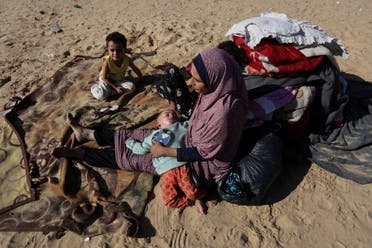 A woman sits with children outside in a camp in Rafah in the southern Gaza Strip, December 6, 2023. (Reuters)