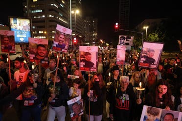 Families of hostages held in the Gaza Strip since October 7 and their supporters, carry pictures and candles as they walk toward a 138-branched menorah, to be lit up on the eve of the first day of Hanukah, in support of the same number of people still held captive, in Tel Aviv on December 7, 2023. (AFP)