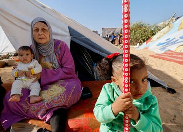 A woman holds a baby next to a girl, as displaced Palestinians, who fled their houses due to Israeli strikes, shelter in a tent camp near the border with Egypt, amid the ongoing conflict between Israel and the Palestinian group Hamas, in Rafah in the southern Gaza Strip, December 11, 2023. (Reuters)