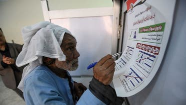 An elderly voter checks the instructions on how to vote before ticking his ballot at a polling station in Cairo's northern suburb of Shubra during the 2024 Egyptian presidential elections on December 10, 2023. The vote in the country of nearly 106 million people will run until December 12, with results expected to be announced on December 18. (Photo by Ahmed HASAN / AFP)