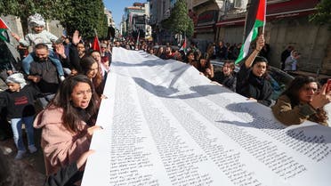 Palestinians carry a list of Gaza victims during a rally amid a general strike in Ramallah city in the occupied West Bank on December 11, 2023, in solidarity with Gaza as battles continue between Israel and the Palestinian militant group Hamas. (Photo by Jaafar ASHTIYEH / AFP)