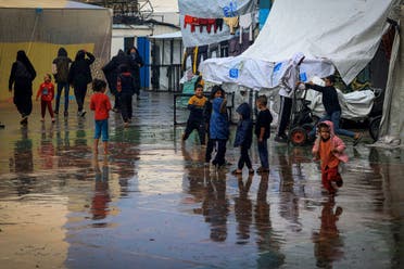 Palestinian children play amidst the rain at camp for displaced people in Rafah, in the southern Gaza Strip, where most civilians have taken refuge as battles continue between Israel and Hamas, on December 12, 2023. (AFP)