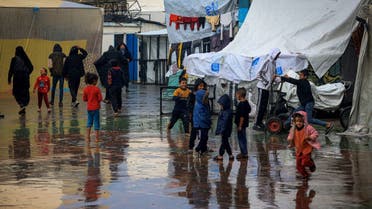 Palestinian children play amidst the rain at camp for displaced people in Rafah, in the southern Gaza Strip, where most civilians have taken refuge as battles continue between Israel and Hamas, on December 12, 2023. (AFP)
