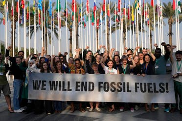 Members of Greenpeace gather for a photo around a sign that reads we will end fossil fuels at the COP28 UN Climate Summit, Wednesday, Dec. 13, 2023, in Dubai, United Arab Emirates. (AP)