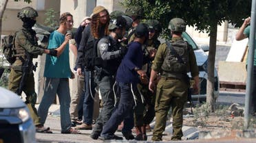 Israeli soldiers restrain Jewish settlers after they stormed the Palestinian West Bank village of Dayr Sharaf, located about seven kilometres (four miles) from the Jewish Einav settlement following the death of an Israeli man on November 2, 2023. (AFP)