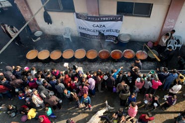 Palestinians gather to receive food cooked by a charity kitchen, amid the ongoing conflict between Israel and Hamas, in Rafah in the southern Gaza Strip, December 17, 2023. (Reuters)
