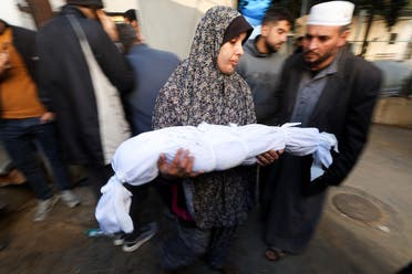 Suzan Zourob, the grandmother of two Palestinian children, a newborn Al-Amera Ayesha and a young boy Ahmed Zourob, who were killed in an Israeli strike, amid the ongoing conflict between Israel and Hamas, holds a child’s body, in Rafah, in the southern Gaza Strip, on December 19, 2023. (Reuters)
