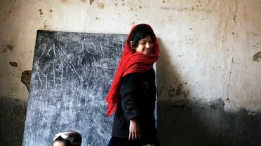 Una niña se aleja de una pizarra después de escribir en ella durante una clase en la ciudad de Kunjak, en la provincia de Helmand, en el sur de Afganistán.  (Reuters)