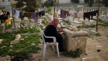 A Palestinian woman, who lives in Sheikh Shaban cemetery, listens to the radio as she sits amongst graves in Gaza City February 23, 2014. (File photo: Reuters)