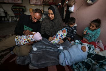 Ammar and Iman al-Masri, displaced Palestinians who fled from their home in Beit Hanoun to escape Israeli bombardment, hold three of her quadruplets as they take shelter at a school in Deir al-Balah in the central Gaza Strip on December 27, 2023, amid continuing battles between Israel and the militant Hamas group. (AFP)
