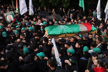 Mourners carry the coffin of Hamas’ deputy leader, Saleh al-Arouri (portrait-R), killed on January 2, 2024 in a strike in Beirut’s southern suburbs, during his funeral procession in Lebanon’s capital on January 4, 2024. (AFP)