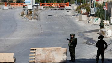 Israeli soldiers stand guard on a blocked road, as the entrance to Hebron is closed, in the Israeli-occupied West Bank, October 8, 2023. (Reuters)